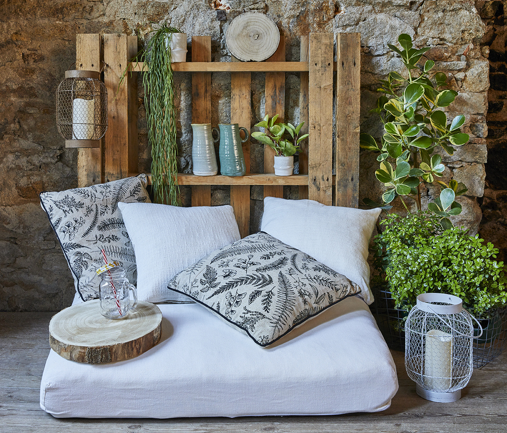décoration en palettes collé au mur avec siège et coussins dessus